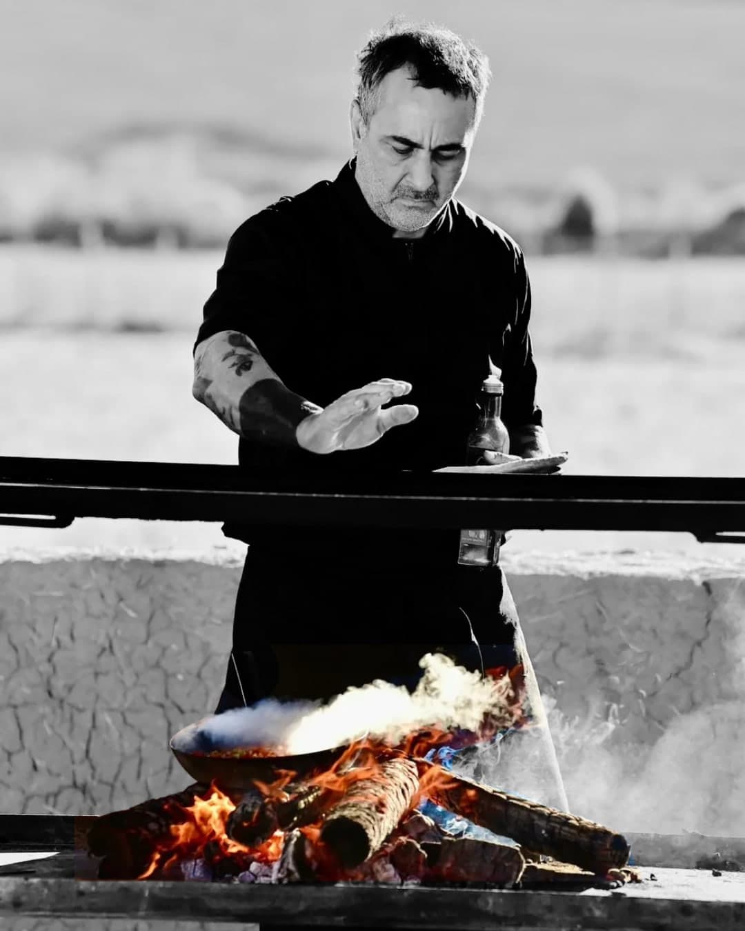 Diego Vega cocinando al fuego; blanco y negro con las llamas en color.